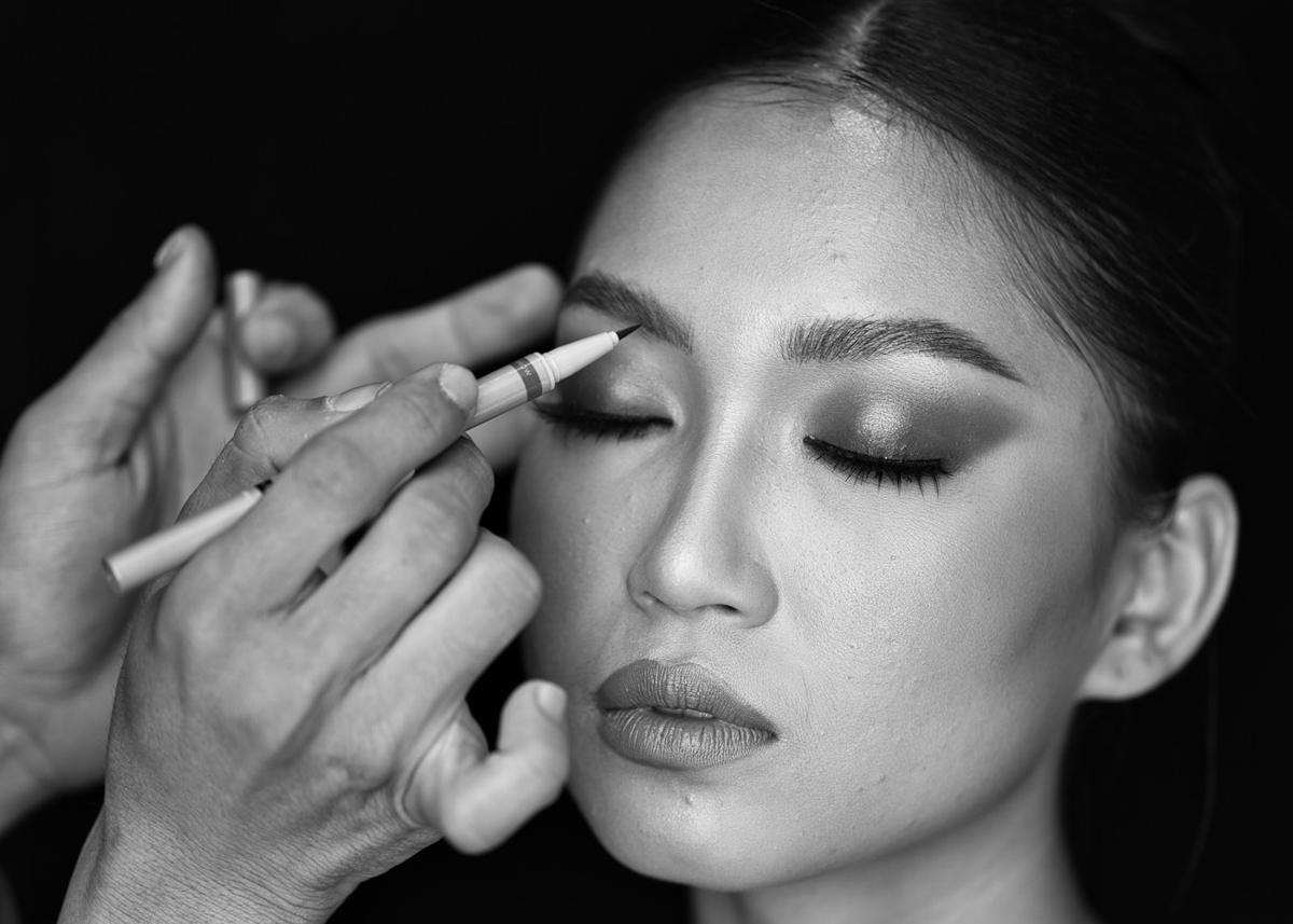 Black and white photo of a makeup artist applying eyeliner