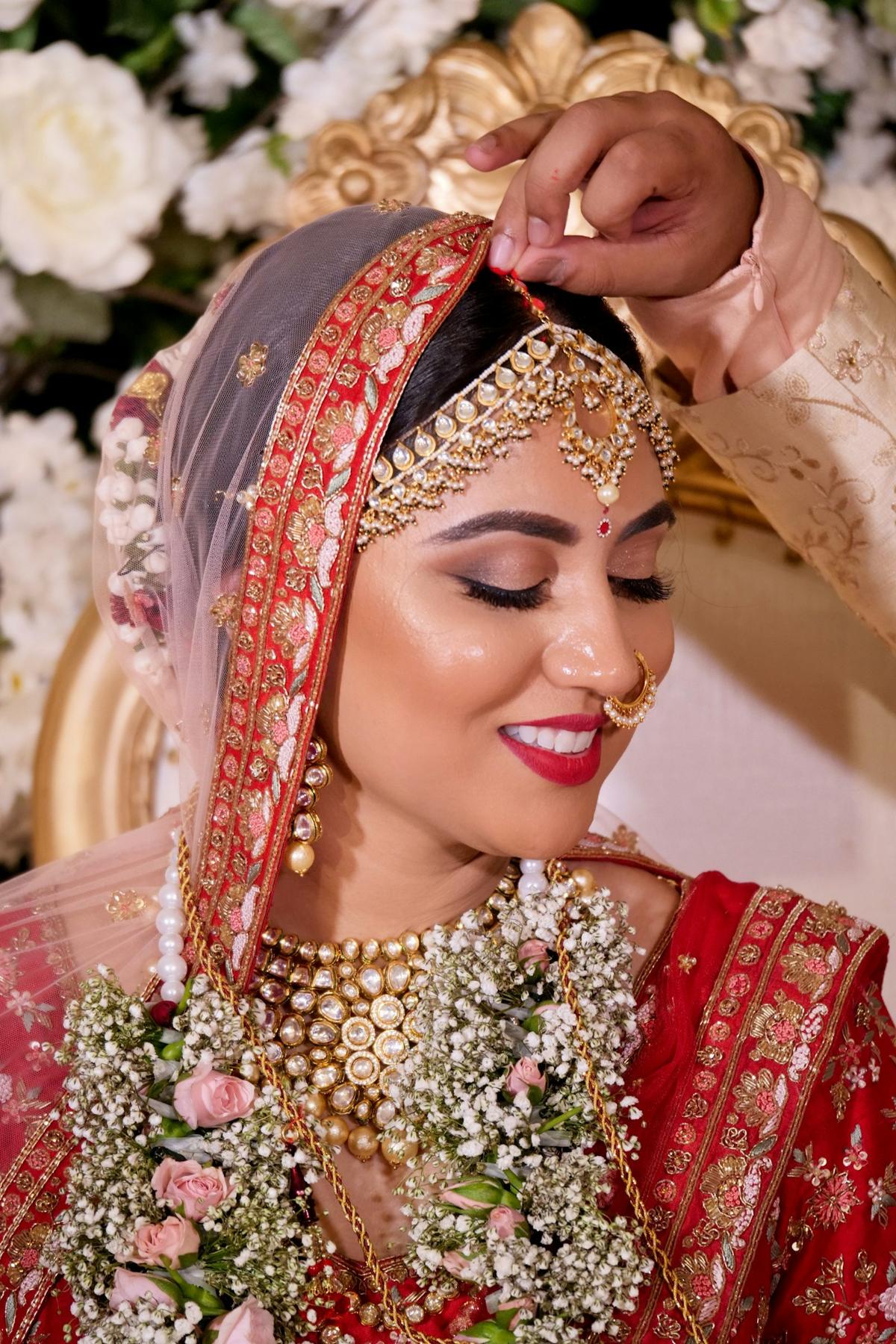 Bride having her maang tikka adjusted before the ceremony