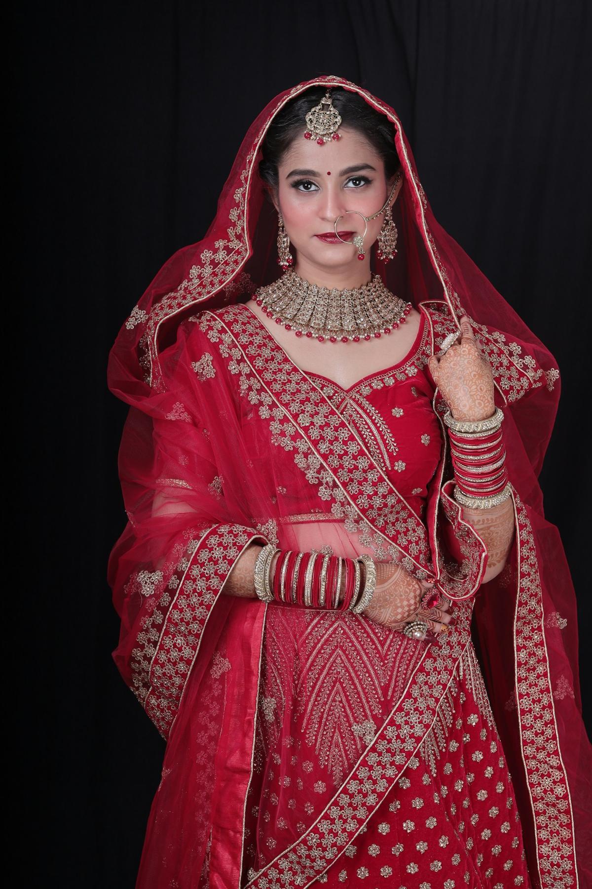 Bride in a red embroidered lehenga with bridal jewellery and chooda