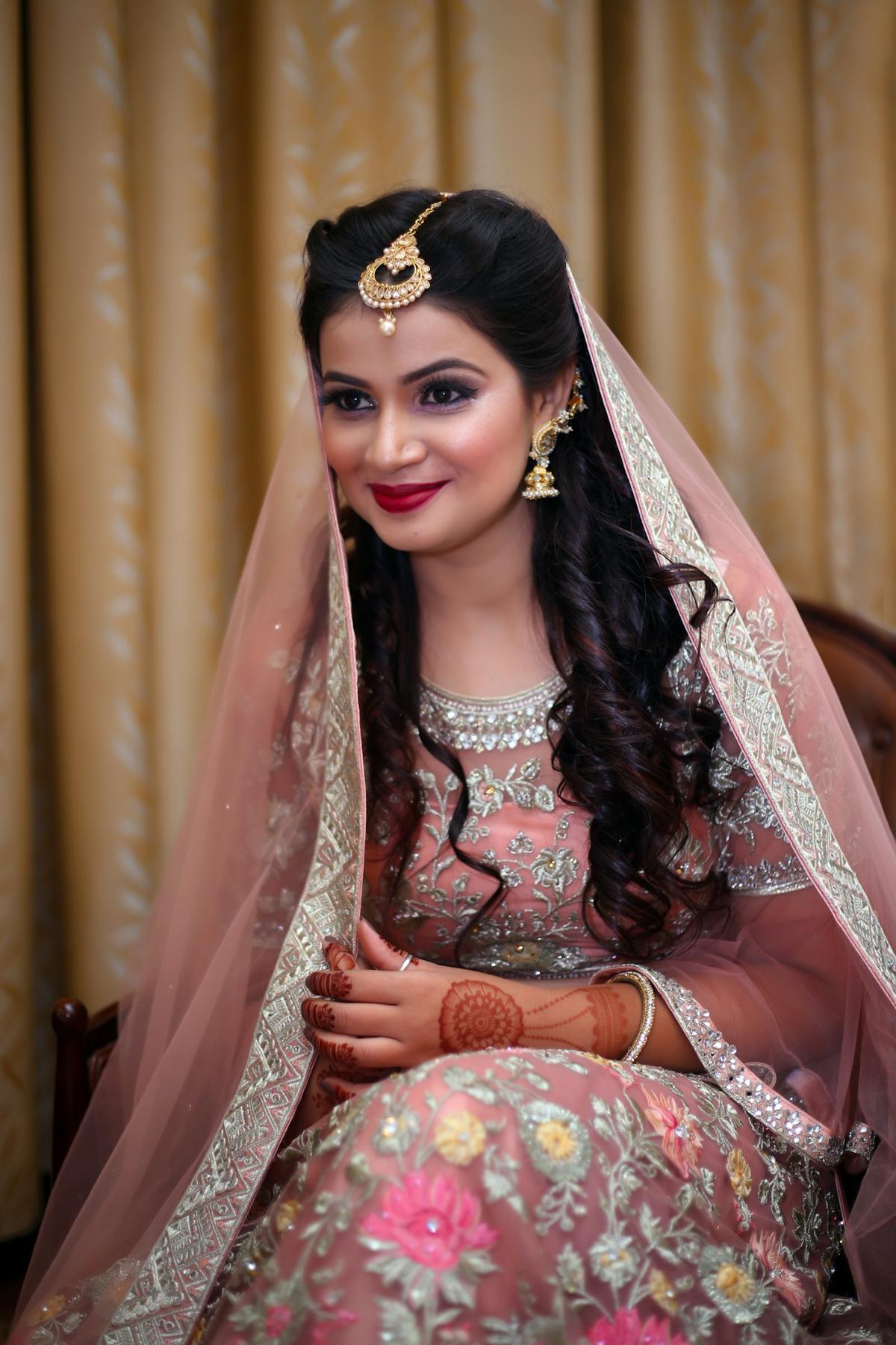 Smiling woman in a pastel embroidered outfit with a soft engagement look