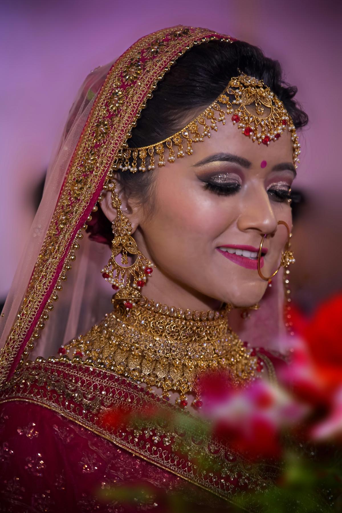 Bride in traditional red attire with ornate gold jewellery and veil